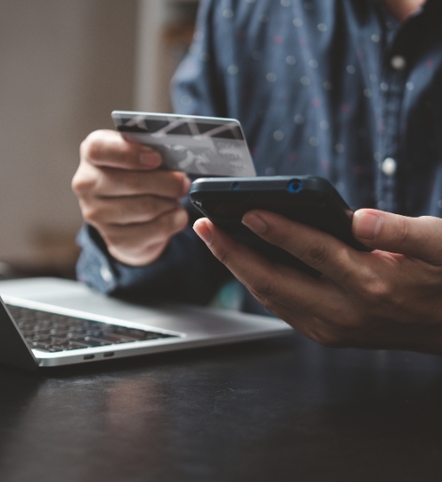  Customer using FABMISR Internet Banking and Mobile Banking on a smartphone and laptop.
