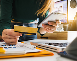 امرأة تحمل بطاقتها وتستخدم تطبيق الهاتف المحمول الخاص بالبنك لإجراء المعاملات