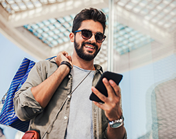 رجل يستخدم هاتفه ويستمتع بخدمات بنك أبوظبي الأول أثناء التسوق