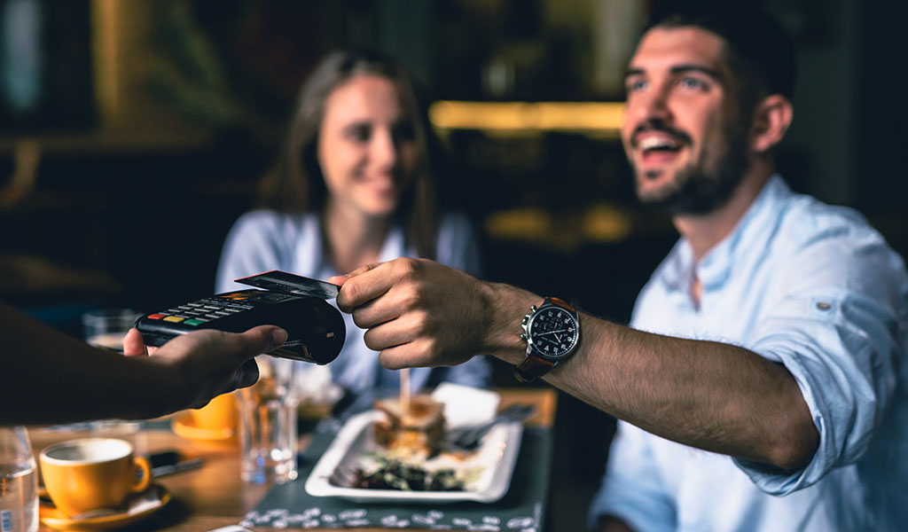 a couple using their card to pay their bill