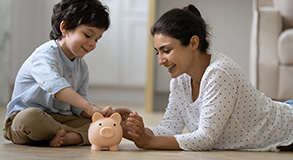 a mother and her kid putting money in a saving box